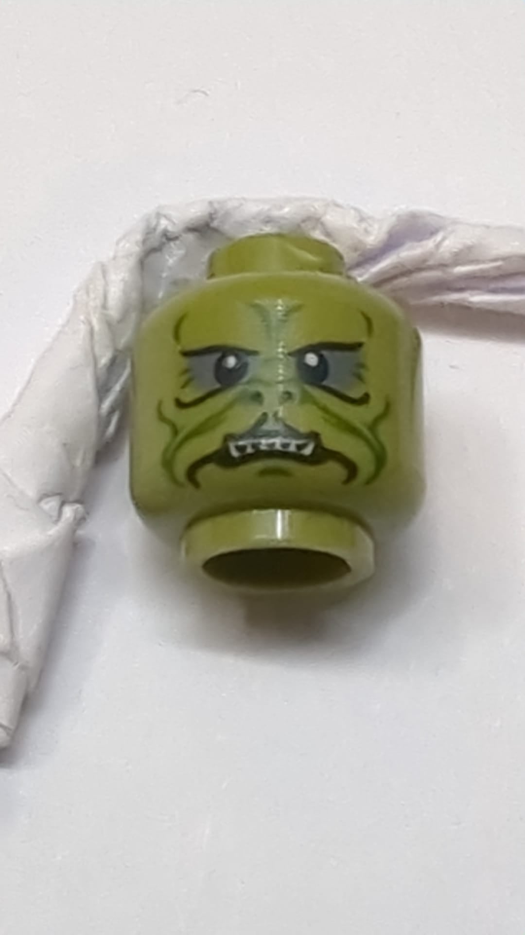 Minifigur, Kopf: Alien SW Klatooinian mit dunkelgrünen Gesichtslinien, Grübchen und Falten am Kinn, dunkelblaugrauem Lidschatten, schwarzen Nasenlöchern und neutralem Gesichtsausdruck mit scharfen unteren Zähnen olivgrün