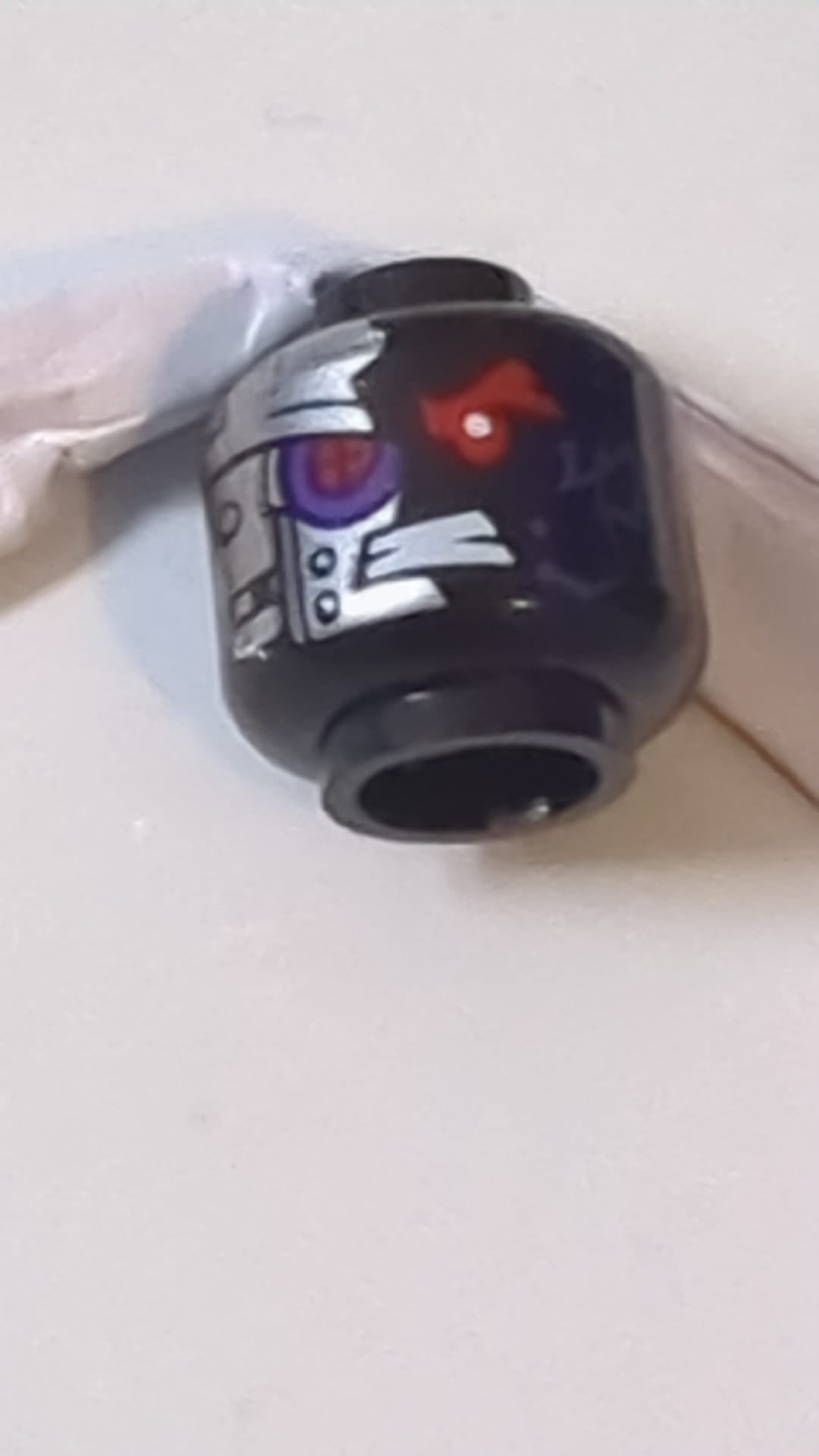 Minifigur, Alienkopf mit rotem mechanischem rechten Auge, dunkelvioletter Schaltkreisen, entblößten Zähnen und silbernen Platten mit Nieten auf Vorder- und Rückseite schwarz