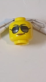 Minifigur, weiblicher Kopf, schwarze Augenbrauen, Sonnenbrille mit dunkelsilbernen Reflexen, mittelbraune Lippen, Grinsen gelb