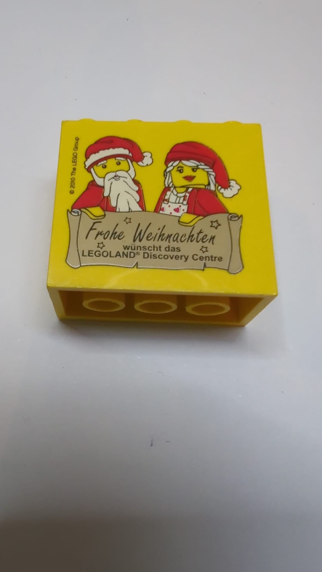 2x4x3 Stein mit dem Muster „Frohe Weihnachten wünscht das Legoland Discovery Center“ gelb