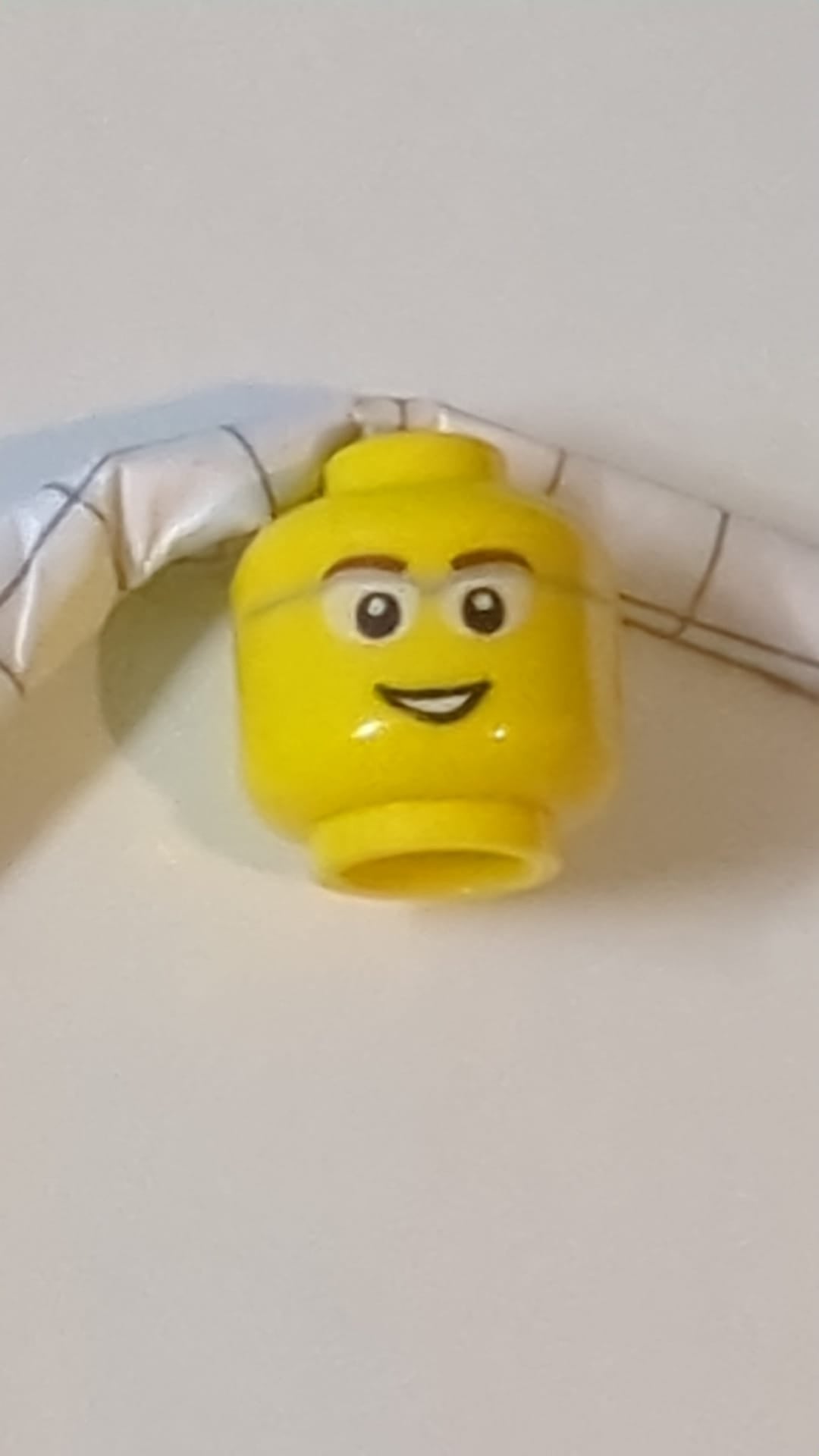 Minifigur, Kopf mit rötlich-braunen Augenbrauen, Brille mit hellblaugrauem Gestell und weißen Gläsern, offener Mund mit Lächeln und sichtbaren Zähnen gelb