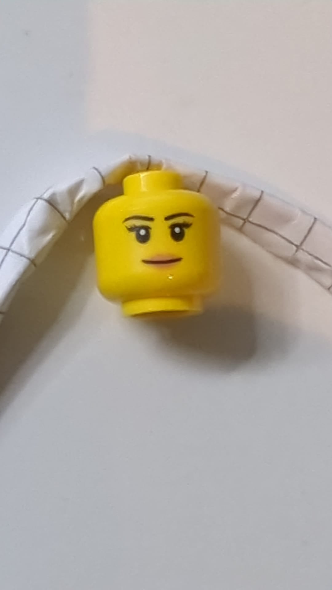 Minifigur, weiblicher Kopf, schwarze, dünne Augenbrauen, Wimpern, nougatfarbene Lippen, grin Muster gelb