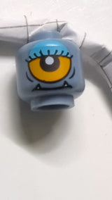 Minifigur, doppelseitiger Alienkopf mit unteren Reißzähnen, Wimpern, einzelnes orangefarbenes Auge offen / Auge halb geschlossen mit blauem Lidschattenmuster sandblau
