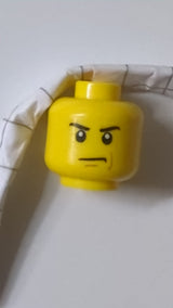 Minifigur, männlicher Kopf mit wütend zusammengezogenen Augenbrauen und finsterem Blick, rotbraunes Linienmuster auf der linken Wange gelb