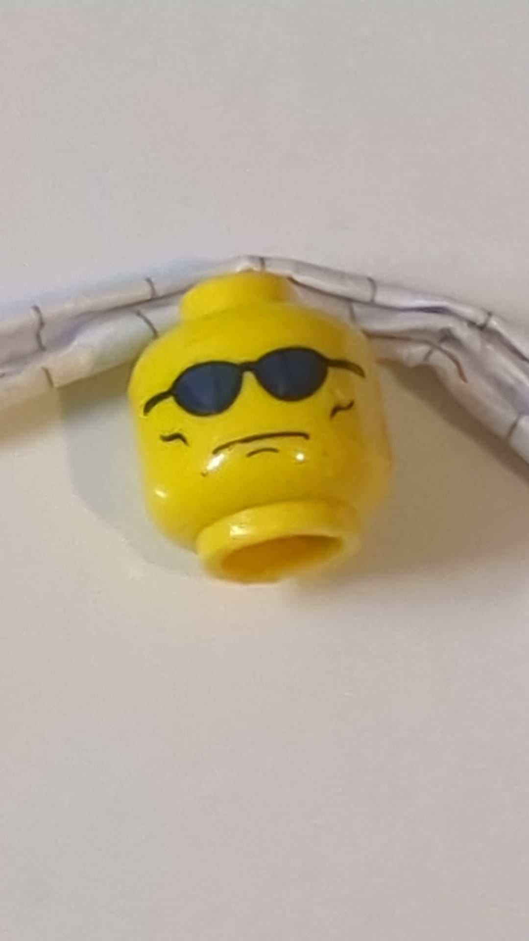 Minifigur, Kopf mit Brille und blauer Sonnenbrille, grimmiges Gesicht mit Faltenmuster auf den Wangen gelb