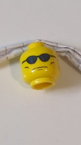 Minifigur, Kopf mit Brille und blauer Sonnenbrille, grimmiges Gesicht mit Faltenmuster auf den Wangen gelb
