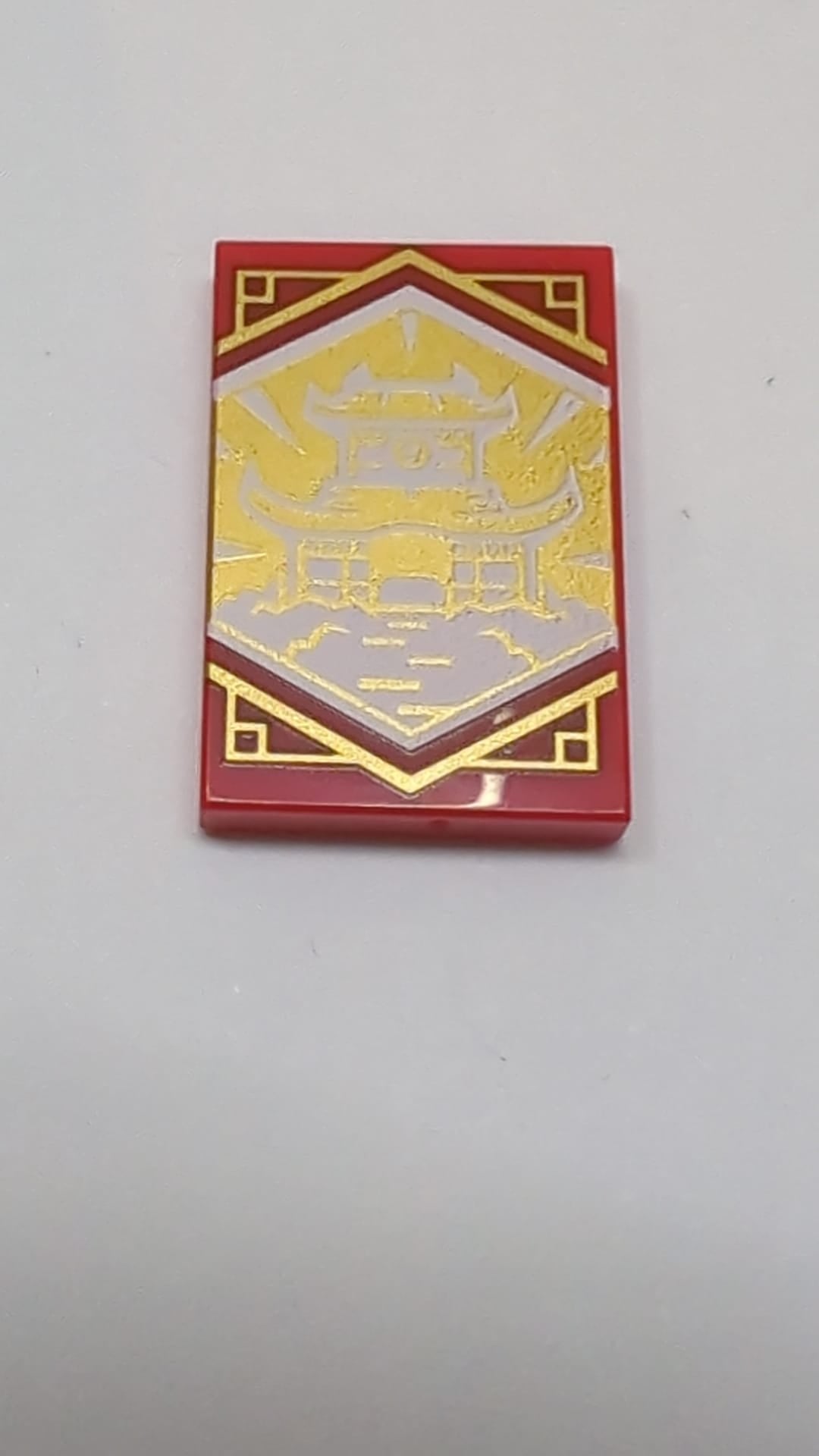 2x3 Fliese mit weißem Dojo-Tempel auf goldenem Hintergrund mit goldenem Zierrandmuster „Ninjago Weisheitsbanner“ rot