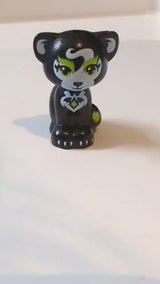 Katze im Mini-Puppen-Stil, sitzend mit limettengrünen Augen und Augenbrauen, schwarzen Wimpern und Nase, weißen Innenohren und Flecken, silbernen Krallen, Diamant mit Fledermausflügel-Symbolmuster „Elfen Jynx“. schwarz