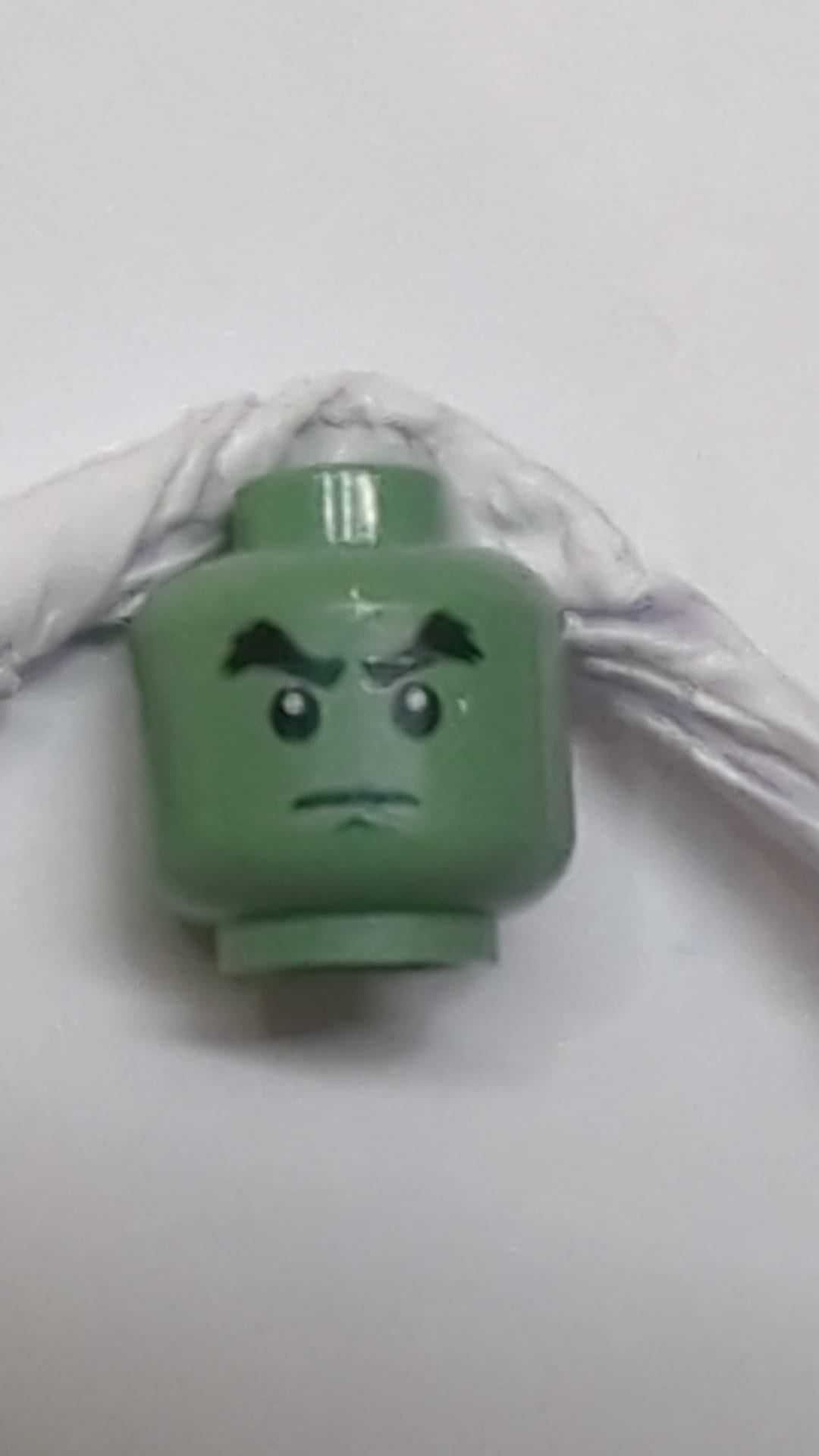 Minifigur, Kopf: Doppelseitig schwarze, buschige Augenbrauen, Grübchen am Kinn, teuflisches Lächeln, Falte unter dem Auge / Entschlossenes Muster sandgrün