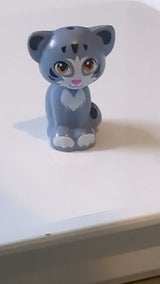 Katze im Mini-Puppenstil, sitzend mit mittelgroßen Nougat-Augen, dunkelrosa Nase, schwarzen Innenohren und Streifen, weißen Flecken und Pfotenmuster „Friends Chico“ sandblau