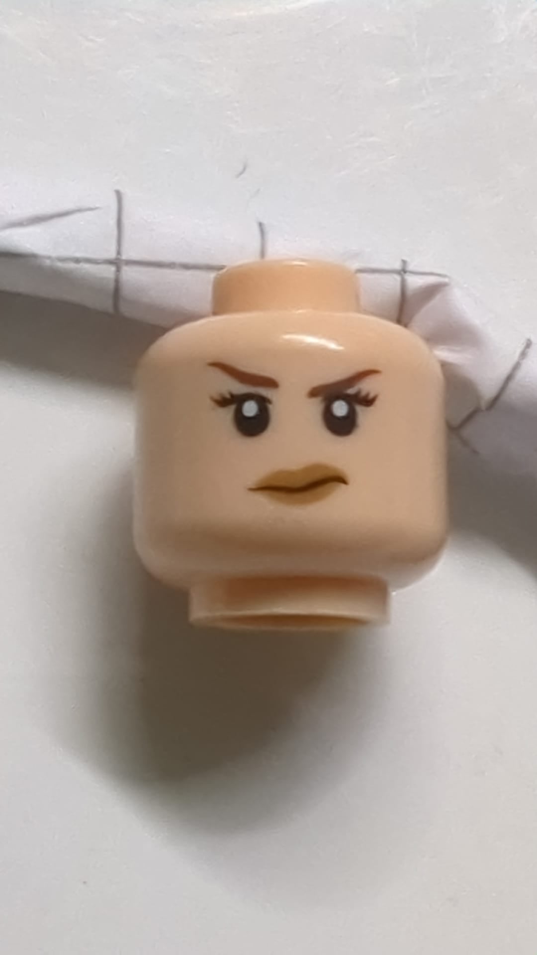 Minifigur, Kopf doppelseitig, weiblich, dunkelbraune Augenbrauen, schwarze Wimpern, nougatfarbene Lippen, schiefes Grinsen/wütender Gesichtsausdruck hellnougat (fleischfarben)