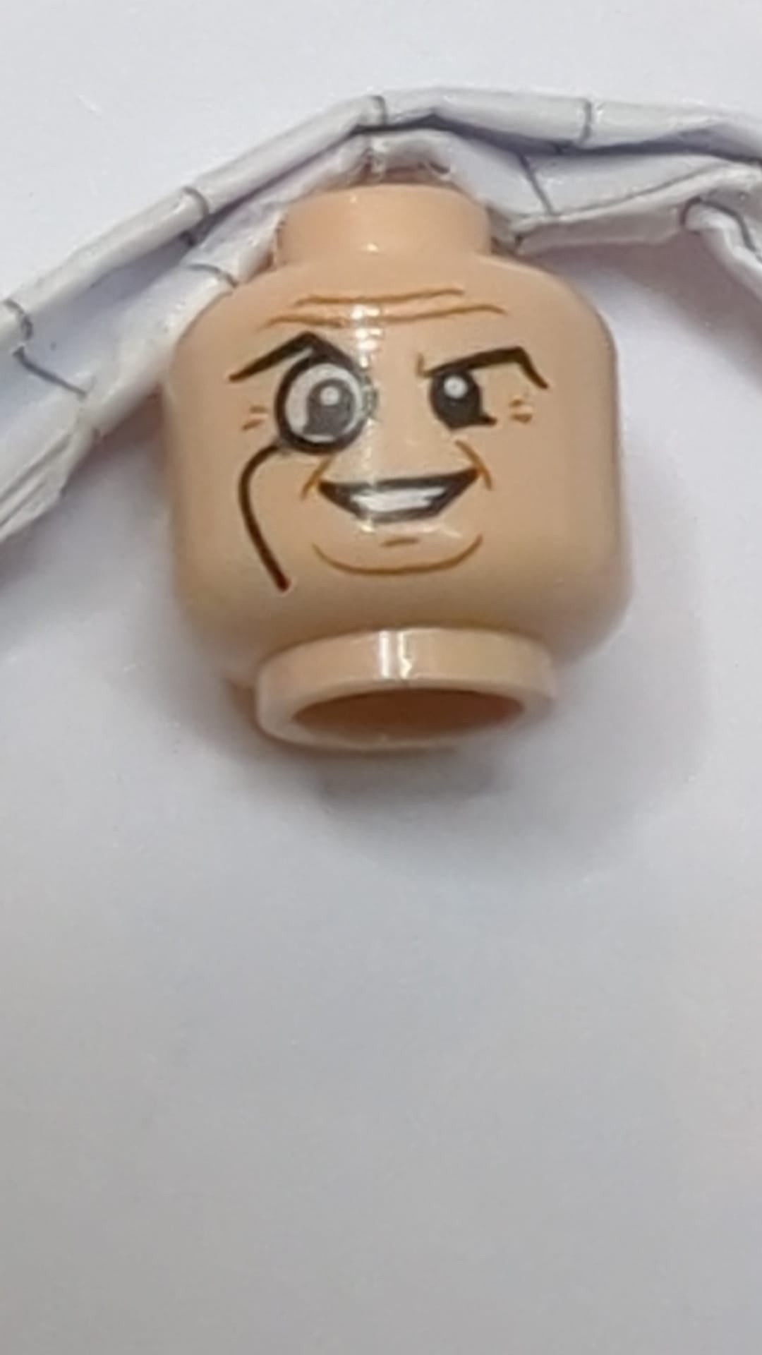 Minifigur, Kopf mit Brille und Monokel, hochgezogene rechte Augenbraue, Falten, Lächelnmuster „Pinguin“ hellnougat (fleischfarben)