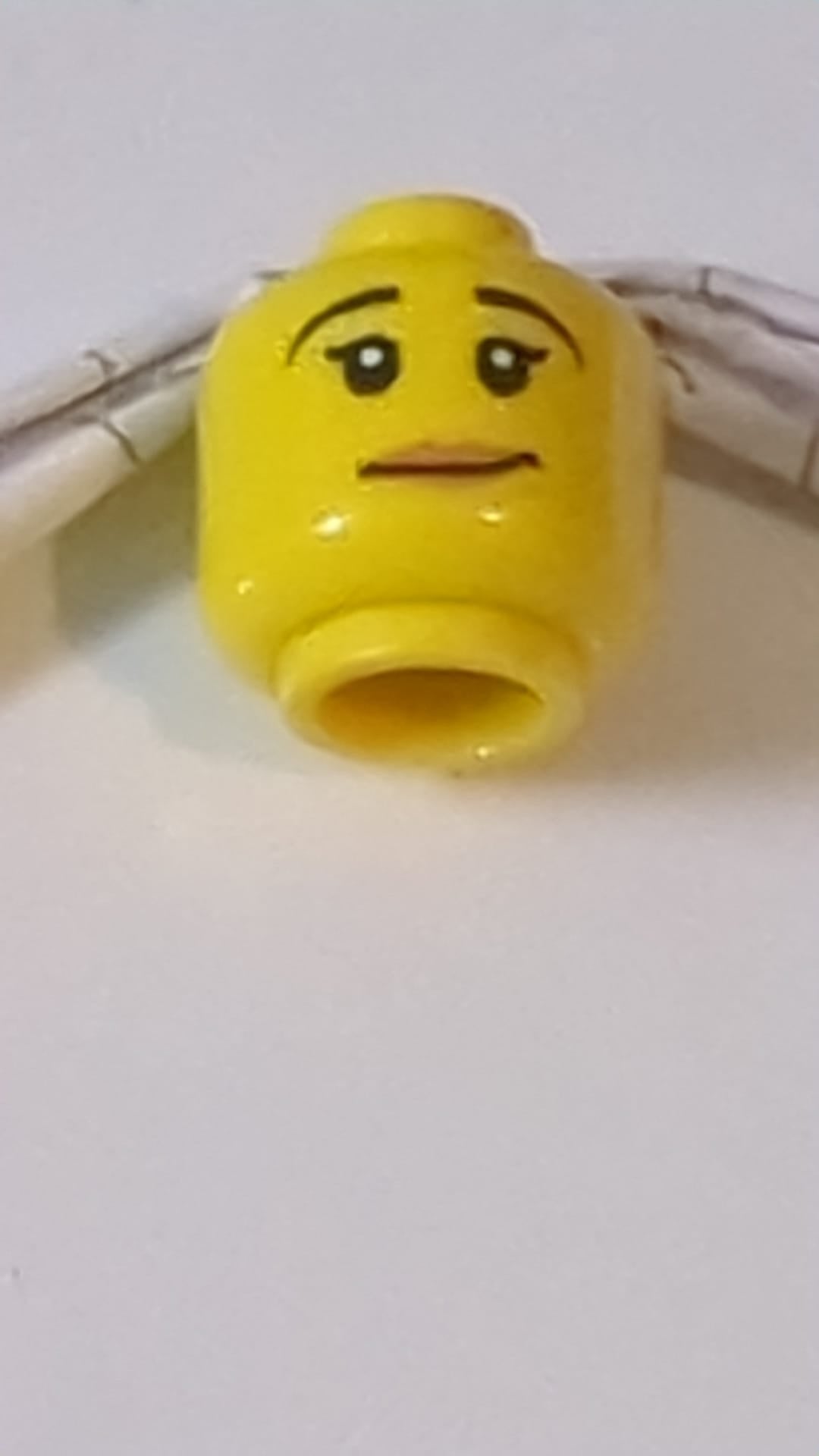 Minifigur, weiblicher Kopf, schwarze Augenbrauen, schiefes Lächeln, pfirsichfarbenes Lippenmuster gelb