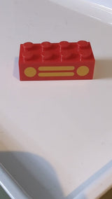 2x4 Stein mit gelbem Kühlergrill und Scheinwerfern, 2 Kreisen und 2 horizontalen Linienmuster rot