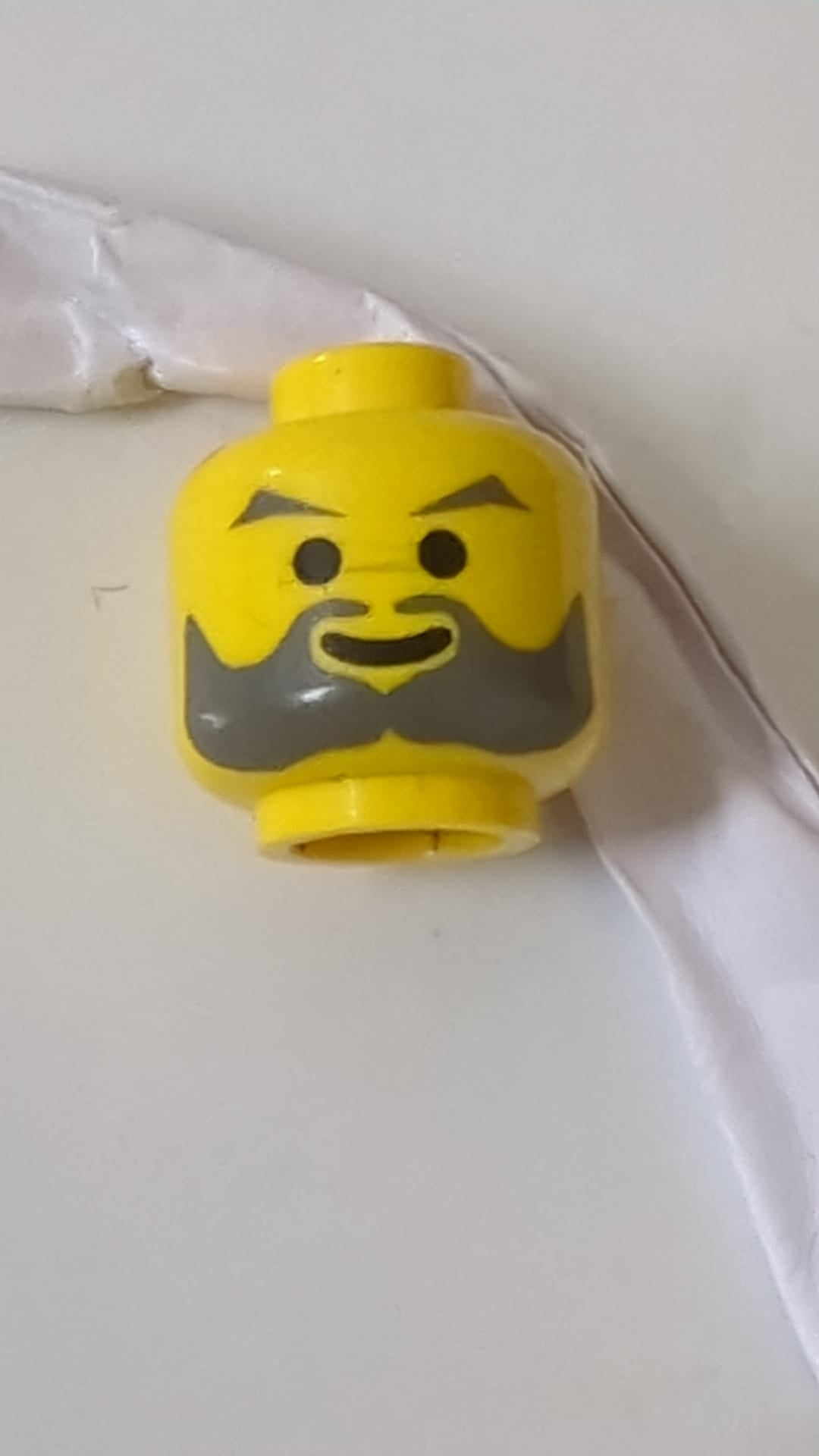 Minifigur, Kopf dunkelgrau, abgewinkelte Augenbrauen und Bart, Standard-Grinsenmuster gelb