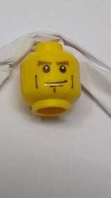 Minifigur, Kopf: rötlich-braun, dichte Augenbrauen, schwarze Wangenfalten und Grübchen am Kinn, Grinsen gelb