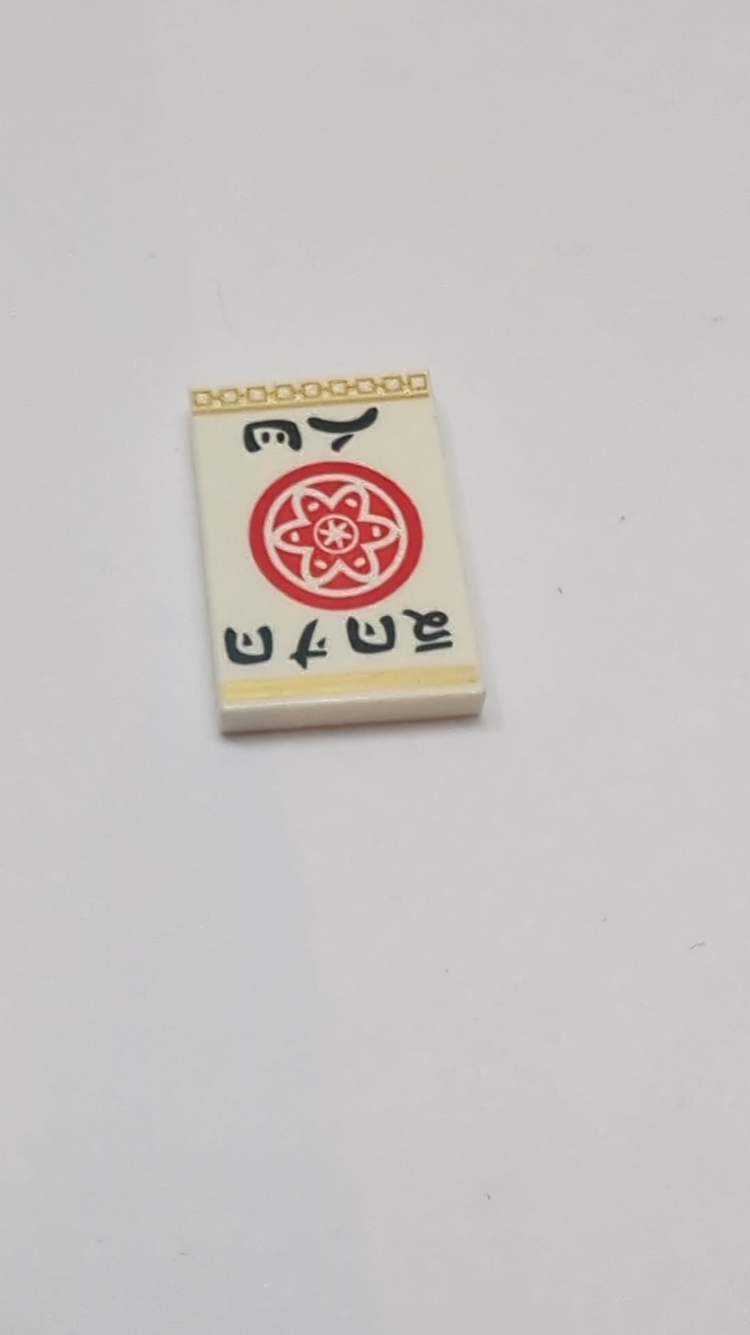 2x3 Fliese mit rotem Kreis mit Blütenblättern und innerem Kreis, Ninjago-Logo „DOJO WU“ und goldenem Randmuster weiß
