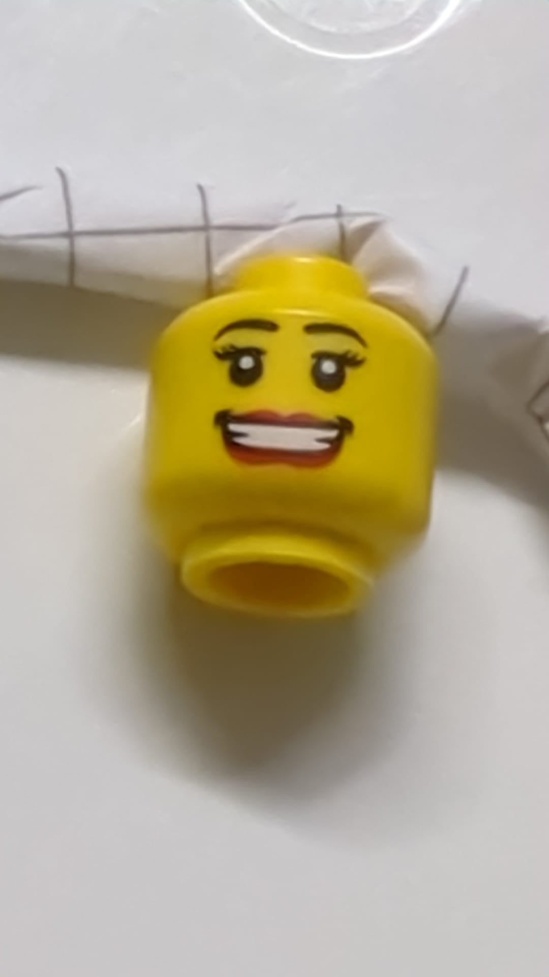 Minifigur, weiblicher Kopf mit schwarzen Augenbrauen, Wimpern, roten Lippen, breitem Mund und Lächeln mit Zähnen und Grübchenmuster gelb