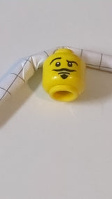 Minifigur, Kopf mit doppelseitigem Schnurrbart, Spitzbart, hochgezogener rechter Augenbraue, Grinsen/offenem Mund, ängstlichem Muster gelb