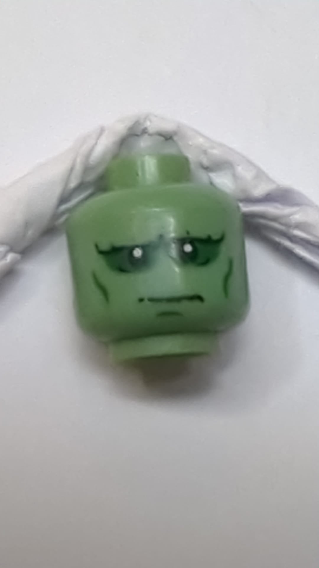 Minifigur, Kopf eines außerirdischen Monsters mit ausgeprägten Augenbrauen, dunkelgrünem Lidschatten und Wangenfalten, strenges Muster sandgrün