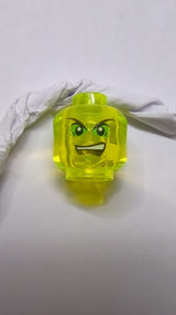 Kopf mit schwarzen spitzen Augenbrauen, leuchtend grünem Lidschatten, geöffnetem Mund mit finsterem Ausdruck und sichtbaren oberen Zähnen transparent neongrün