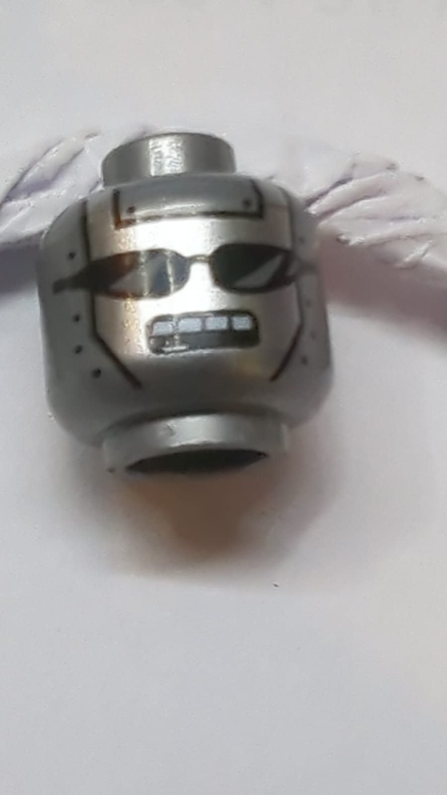 Kopf eines außerirdischen Roboters mit silbernem Gesicht, schwarzen Sonnenbrillen, Nieten und offenem rechteckigem Mund mit weißem Zahn-Muster pearlsilber