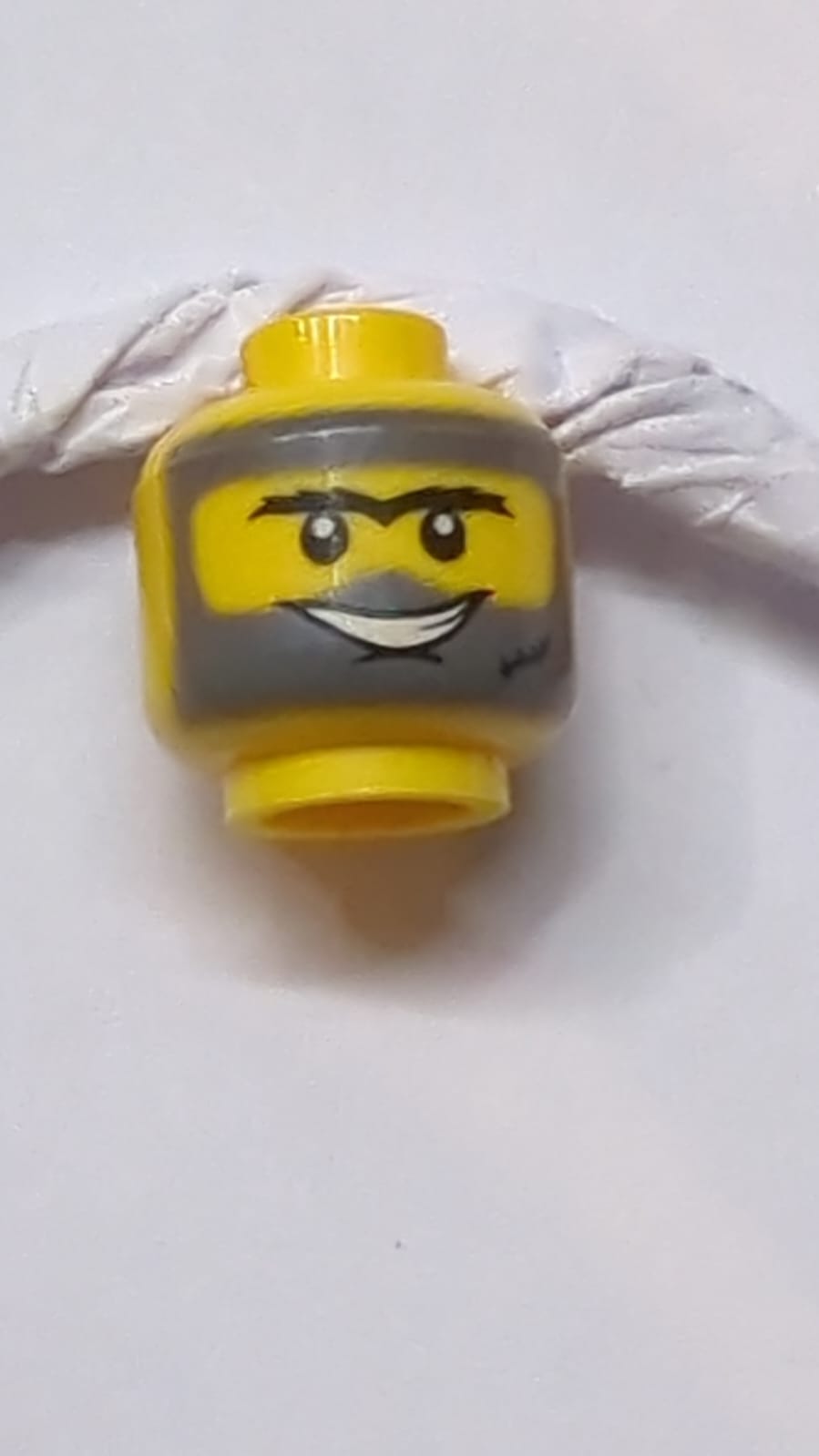 Kopf mit doppelseitiger schwarzer buschiger Monobraue, Kinngrübchen, Narbe, dunkelbläulich-graue Schmutzflecken, zusammengebissene Zähne / offene Mundlächeln-Muster gelb