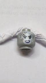 Kopf einer weißen Frau mit dunklen bläulich-grauen Tätowierungen im Gesicht, dunklem lila Lidschatten und Lippenmuster neuhellgrau