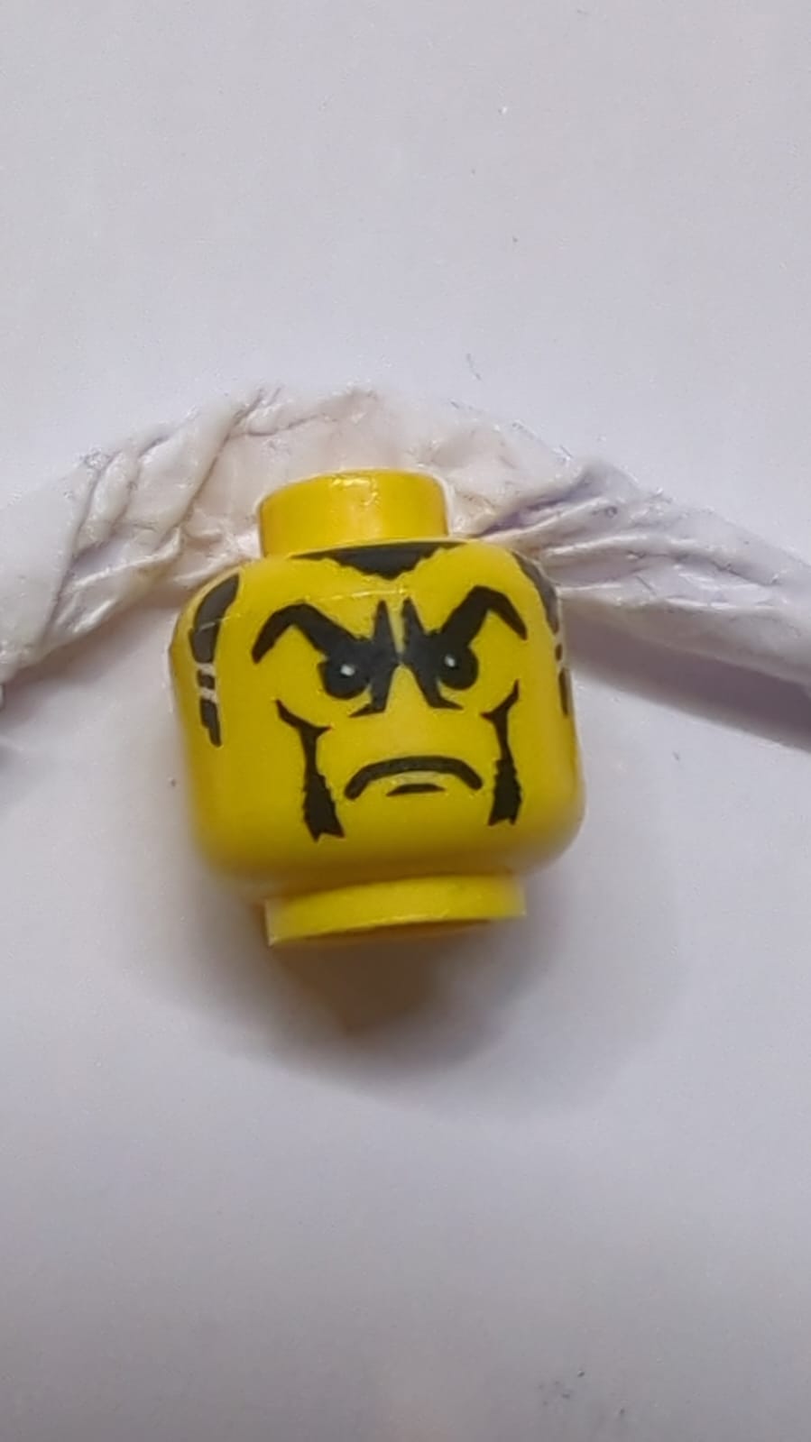 Kopf mit schwarzen buschigen Augenbrauen, welligem Schnurrbart und Kinnbart, standardmäßiges Grinsen gelb