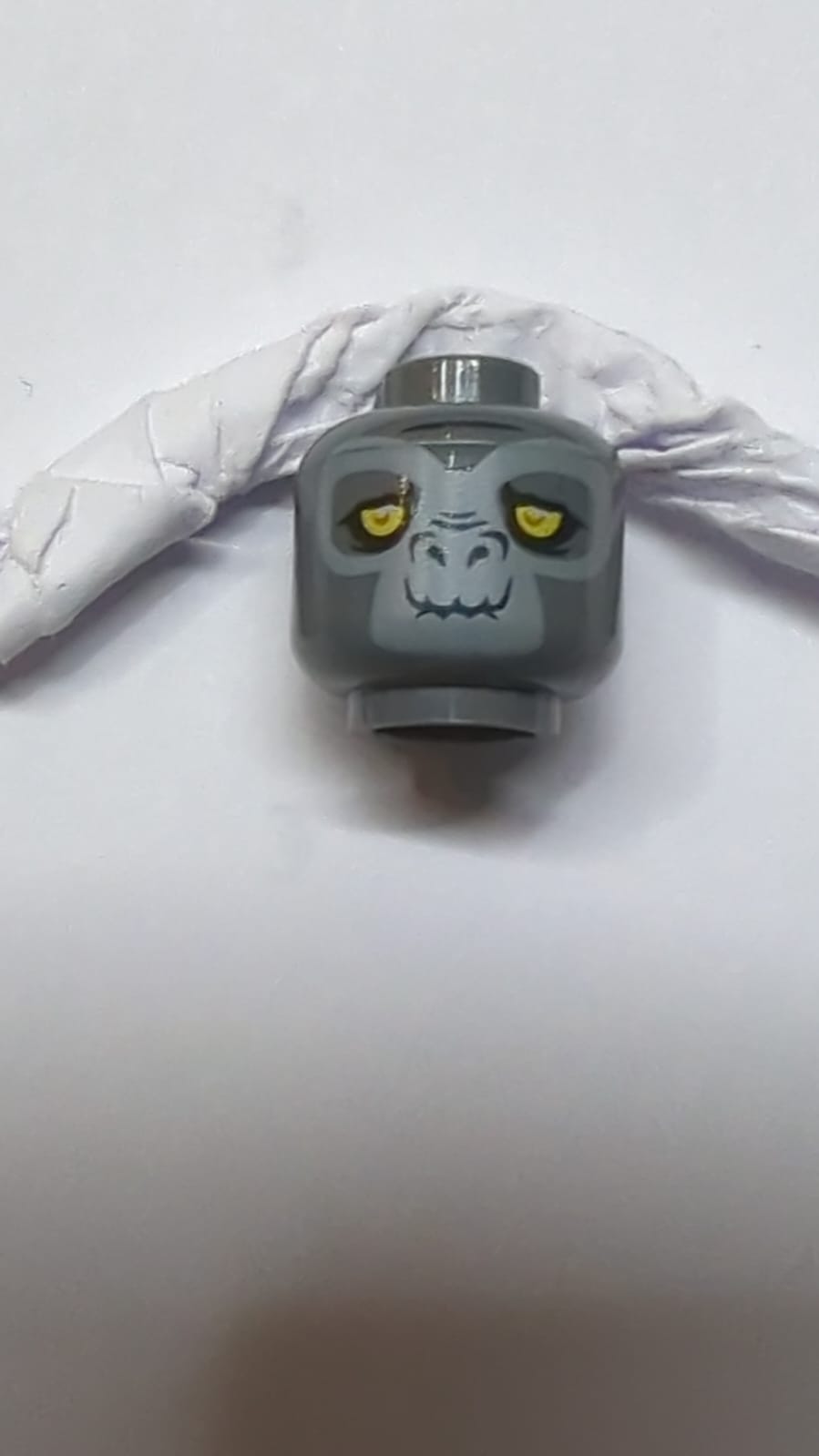 Kopf eines doppelseitigen Alien-Chima-Gorillas mit leuchtend gelben Augen und hell bläulich-grauem Gesicht, Grinsen / schief offenes Mundlächeln mit Zahnmuster neudunkelgrau