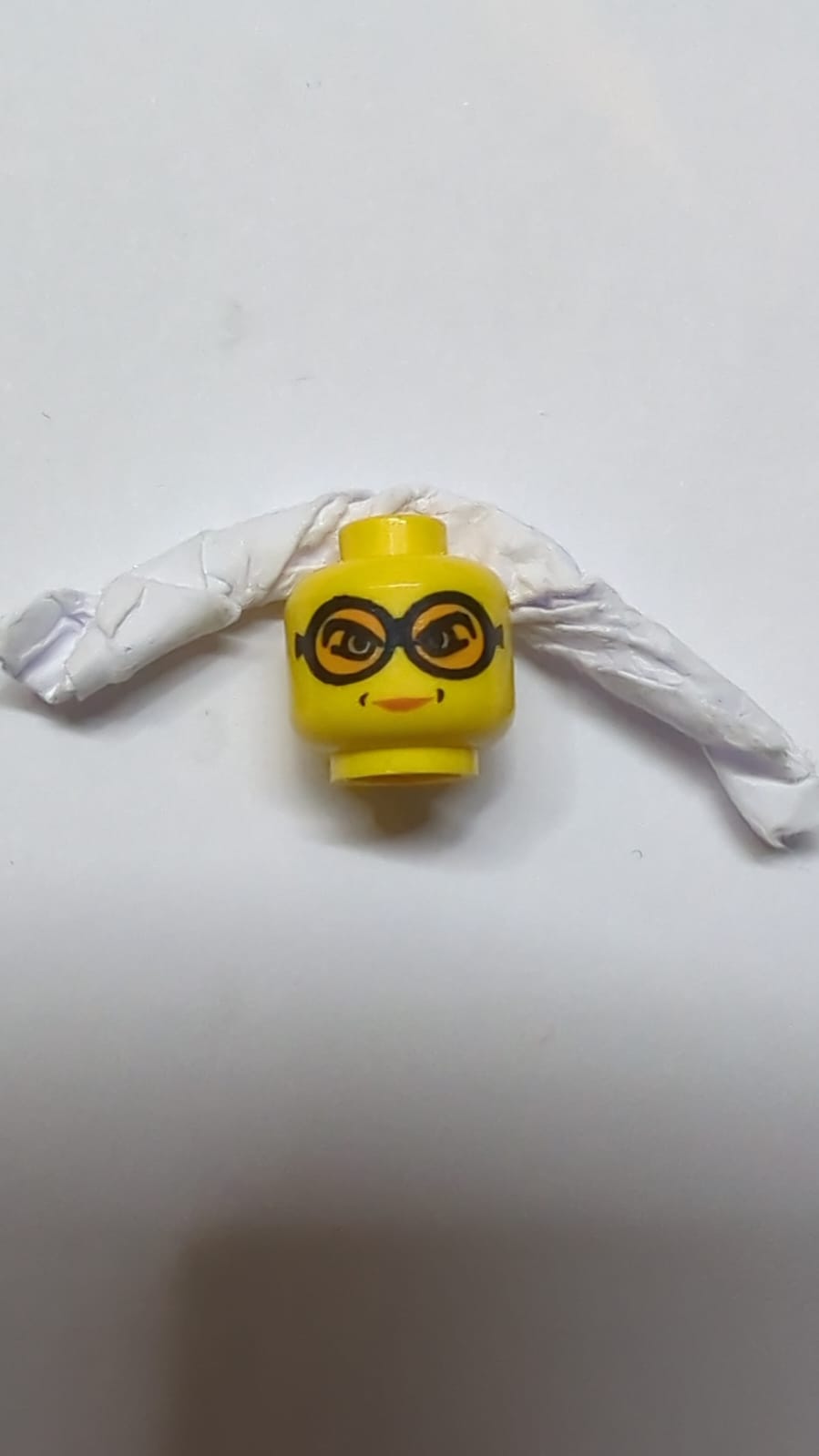 Kopf einer weiblichen Figur mit Brille und orangefarbenen Schutzbrillen, Grübchen um das Lippenmuster gelb