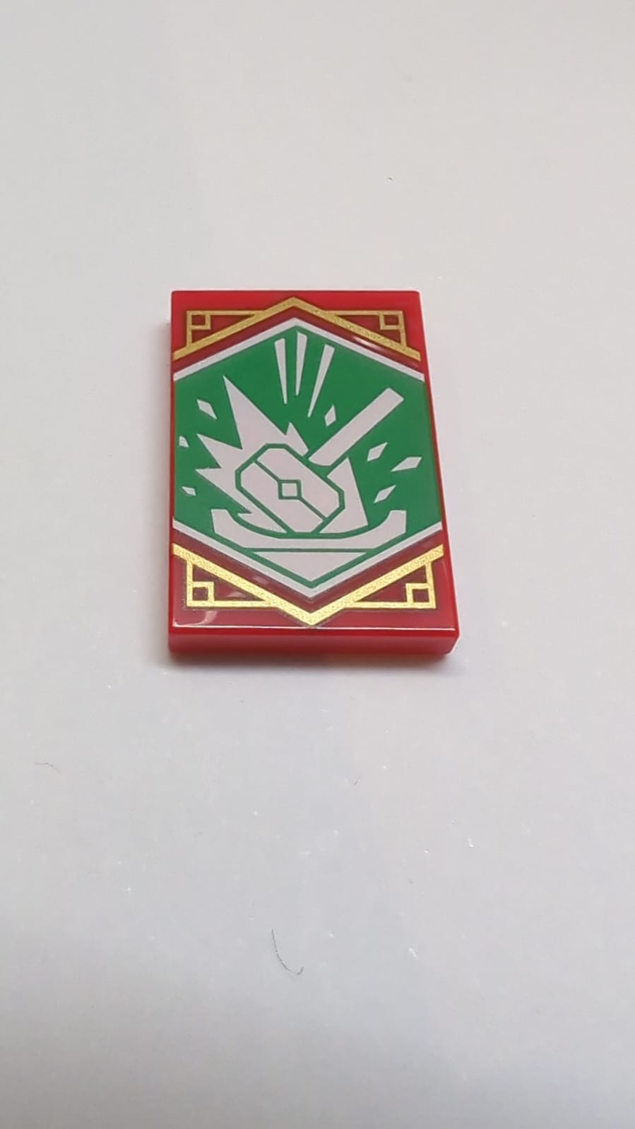 NEU Fliese 2 x 3 mit weißem Hammer mit Energiewellen auf grünem Hintergrund mit Goldrandmuster (Ninjago Banner) rot