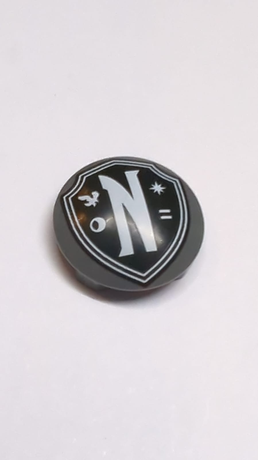 NEU Platte, rund 2 x 2 mit abgerundetem Boden (Boot-Noppe) mit schwarzem Nevermore Academy Wappenemblem mit weißem Rand, Buchstabe N, Rabe, Mond, Stern und Gleichheitszeichen-Muster neudunkelgrau