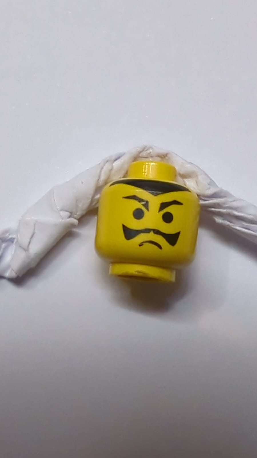 Kopf mit schwarzen spitzen Augenbrauen, Schnurrbart und Haaransatz, Stirnrunzelmuster gelb