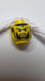 Kopf mit schwarzem Bart und gestutztem Kinn, vollen Wangen, gestreiften Koteletten, finsteren Augenbrauen, Pupillenmuster (Schattenritter) gelb