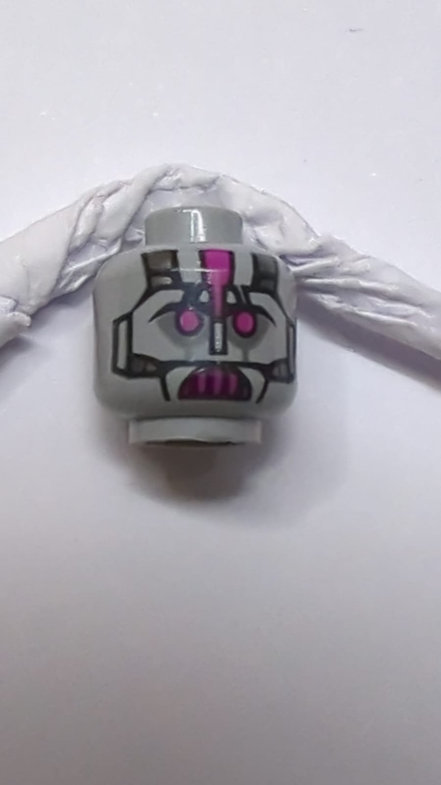 Kopf eines Außerirdischen mit Roboter-Augen und -Mund in Magenta und Metallplattenmuster neuhellgrau