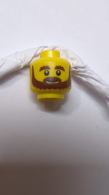 Kopf mit braunem Bart, buschigen Augenbrauen, Grinsen und weißen Pupillenmuster gelb