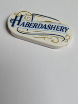 NEU Fliese, rund 2 x 4 oval mit dunkelblauem und mittlerem blauem 'HABERDASHERY' und goldenem Rankenmuster weiß