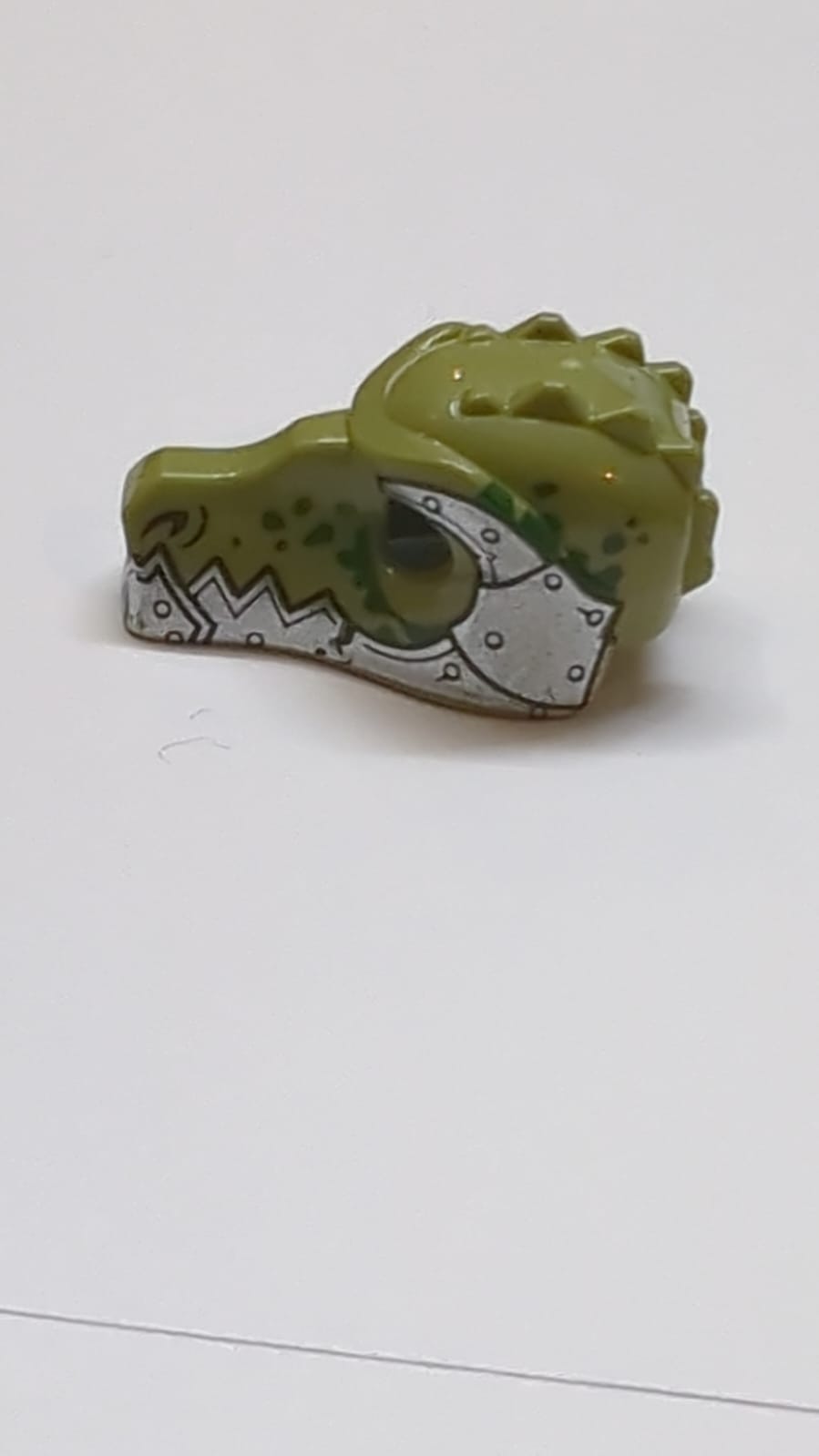 Minifigur, Kopfbedeckung: Krokodilmaske mit metallisch-silbernem Unterkiefer und Panzerung mit Nieten und dunkelgrünem Fleckenmuster olivgrün