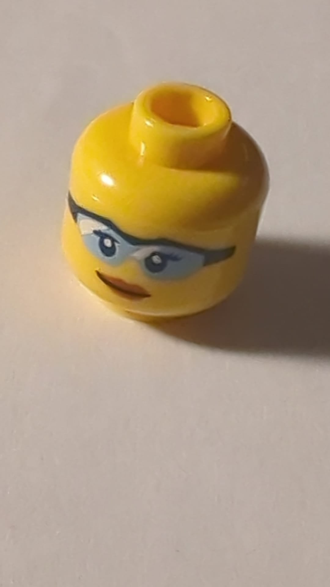 NEU Minifigur, Kopf weiblich mit dunkelblauen Augen und Wimpern, Schutzbrille mit hellblauen Gläsern und weißen Reflexen, dunkelorangefarbene Lippen, leicht schiefes Grinsen-Muster gelb