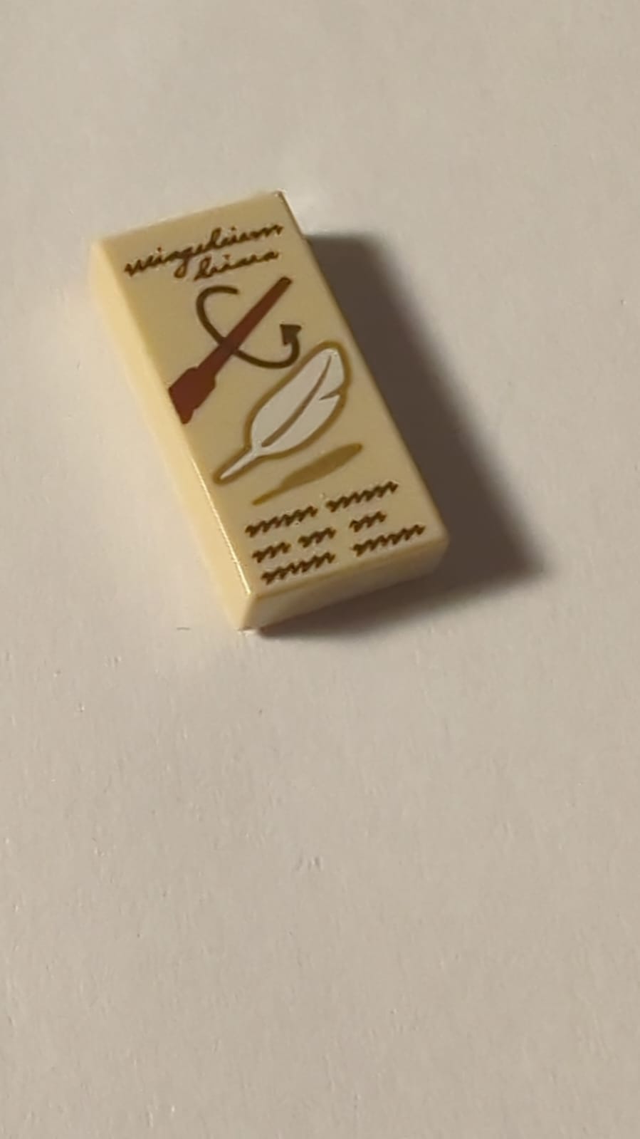 NEU Fliese 1 x 2 mit dunkelbraunem Schriftzug 'wingardium leviosa' und Kritzeleien, rötlich-brauner Zauberstab, weißes Feder-Muster beige
