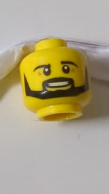 Minifigur, Kopf mit schwarzen Augenbrauen, Schnurrbart und kantigem Bart, mittelbraunen Falten, offenem Mund mit sichtbarem Lächeln und Zahnmuster gelb