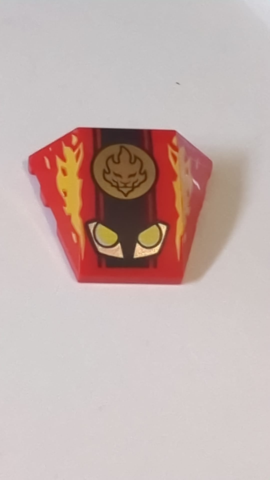 4x3 Keilstein Dreifach gebogener Stein ohne Noppen mit gelben und silbernen Scheinwerfern, goldenem Ninjago-Feuerkraft-Emblem und Flammenmuster rot