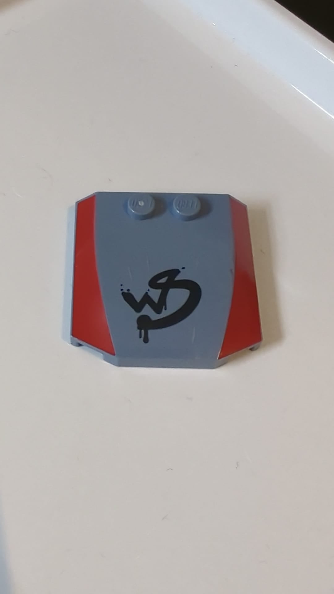 4x4x2/3 Keil dreifach gebogen, mit roten Seiten und grob bemaltem „WS“-Graffiti-Muster sandblau