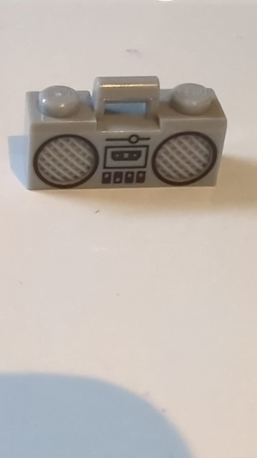 Minifigur-Zubehör: Radio-Boombox mit Griffstange sowie Aufdruck von schwarzem Kassettendeck, Schaltern und Lautsprechern mit Umrandung neuhellgrau