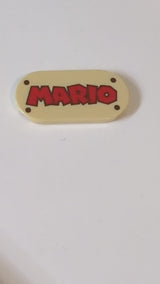 2x4 Fliese, rund (oval) mit rotem „MARIO“-Schriftzug und dunkelbraunem Nietmuster beige