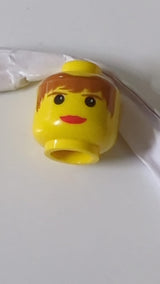Minifigur, weiblicher Kopf mit roten Lippen, braunem Haar und Augenbrauenmuster gelb