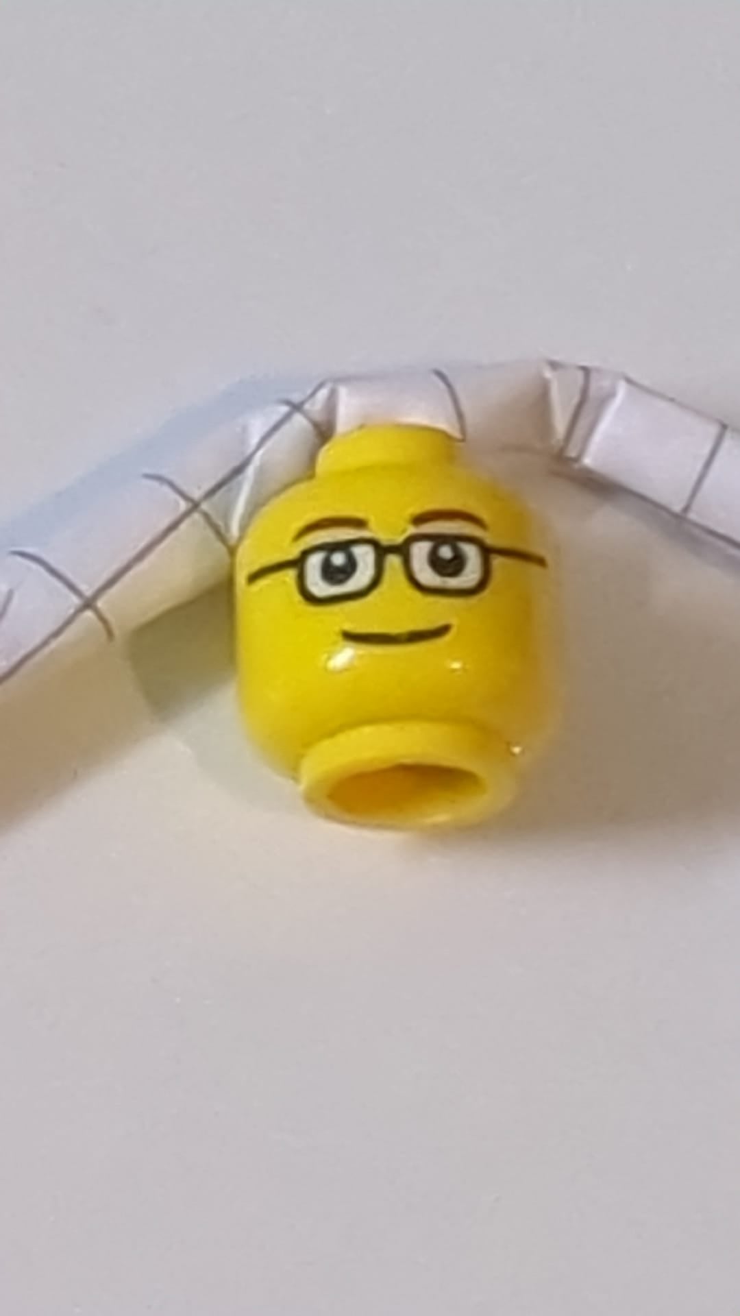Minifigur, rechteckiger Kopf mit Brille, dünne braune Augenbrauen, Lächeln gelb