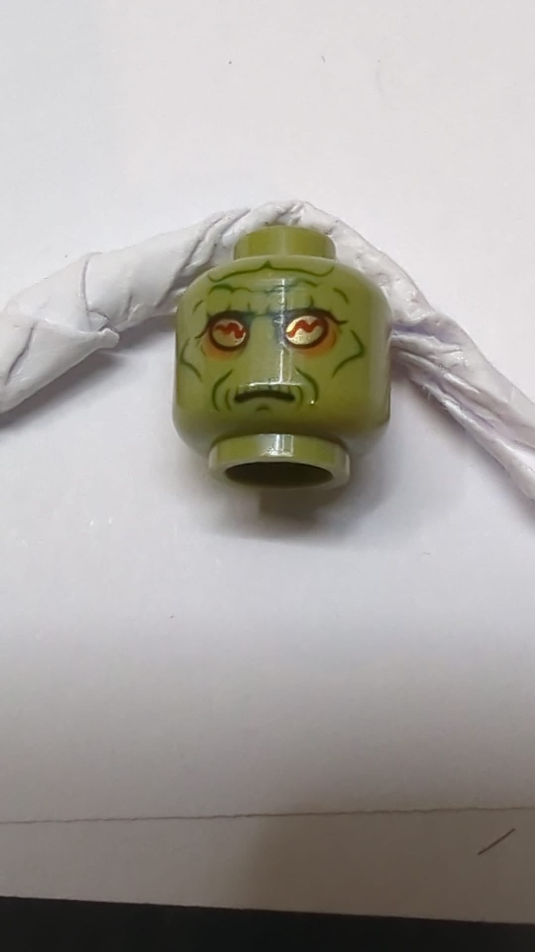Minifigur, Kopf: Alien SW Neimoidian mit goldenen Augen, dunkelorangefarbenem Lidschatten, dunkelgrünen Wangenfalten, Falten am Kinn, Grübchen und Falten, ausgeprägten Augenbrauen und neutralem Muster olivgrün