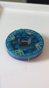 6x6x1 1/3 Ninjago Spinner (runde Basis) mit transparent-hellblauer Oberseite und im Dunkeln leuchtenden Totenköpfen auf mittelblauem Muster lila